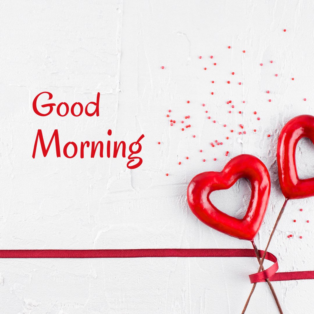 Good morning heart image with two glossy red heart-shaped decorations on a rustic white wall, accented with scattered red confetti and a deep red ribbon stretching across the composition, evoking a message of love and warmth.